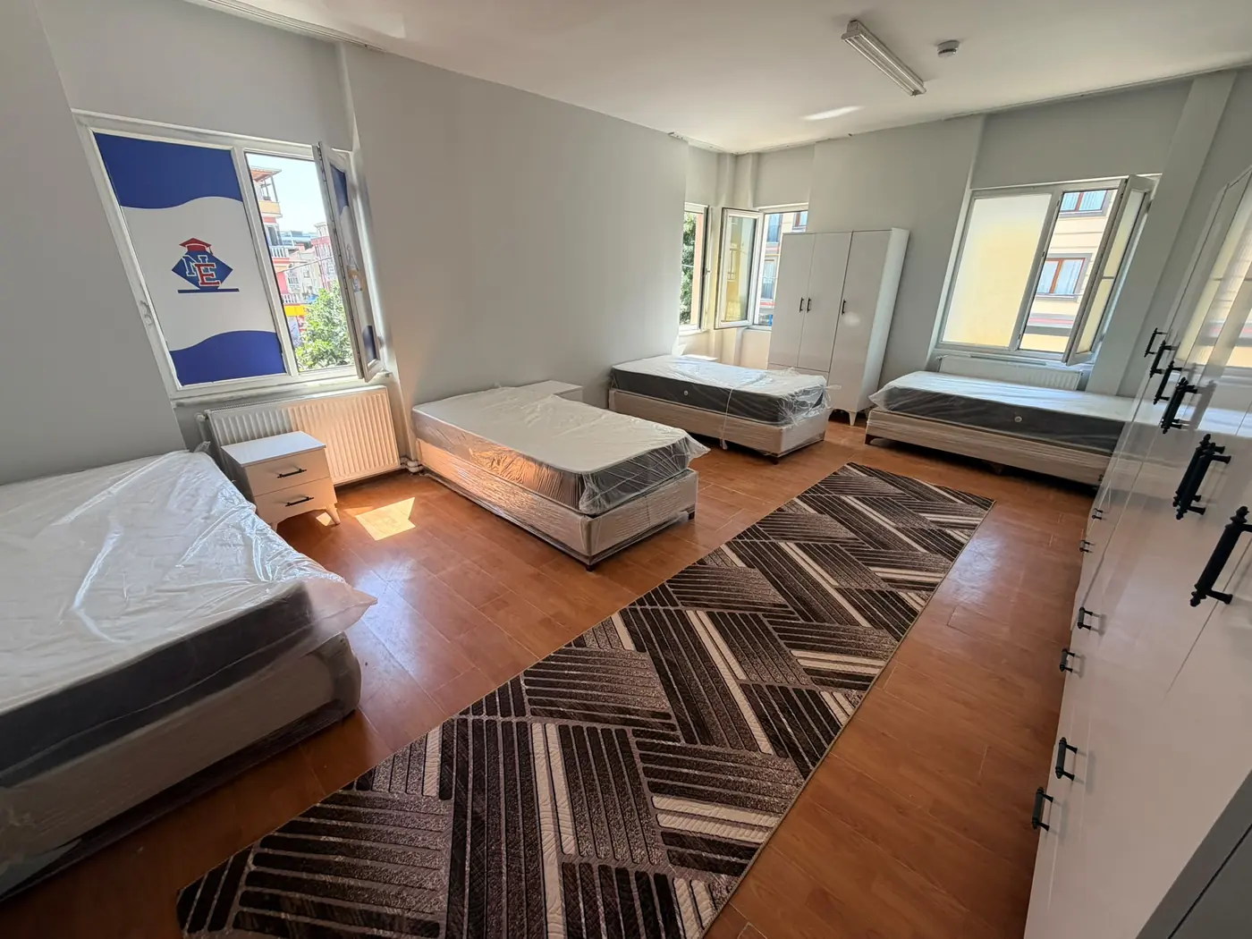 A quad room at Kıvanç Kız Yurdu with four single beds, wardrobes and a study set
