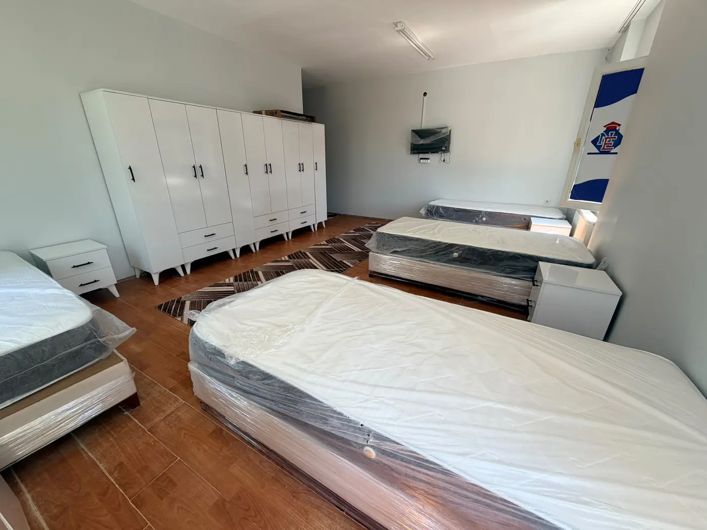 A quad room at Kıvanç Kız Yurdu with four single beds, wardrobes and a study set