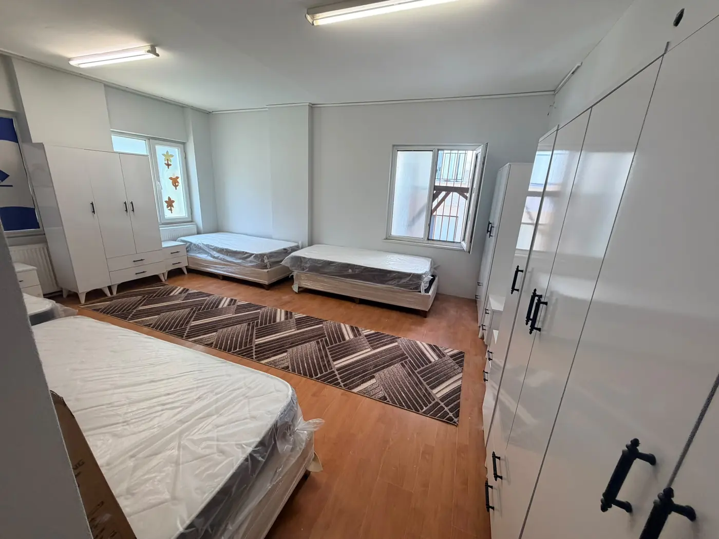 A quad room at Kıvanç Kız Yurdu with four single beds, wardrobes and a study set