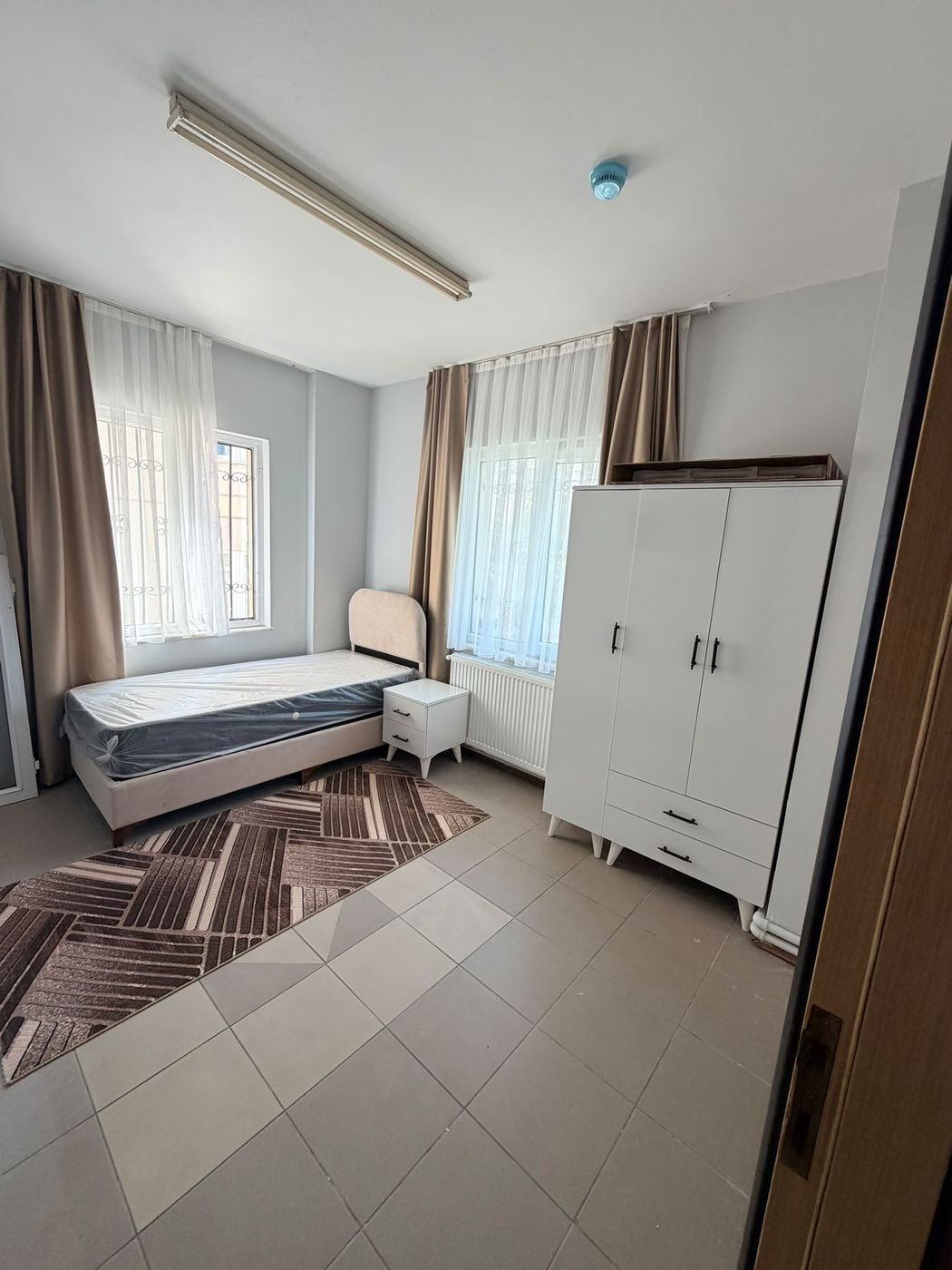 A single room with one bed, a bedside table and a full-height wardrobe